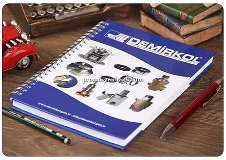 promosyon mavi beyaz baskılı kapaklı metal spiralli katalog defter, ahşap masa üzerinde çapraz çekim