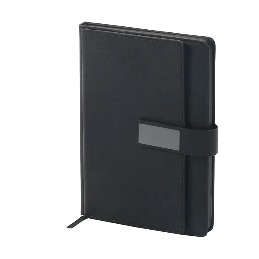 Siyah kapaklı defter; geniş siyah elastik bant üzerinde gri dikdörtgen plaka, altta siyah kurdele.
