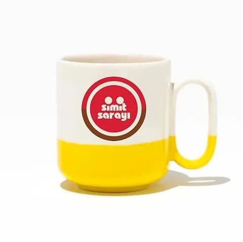 Sarı tabanlı beyaz porselen promosyon kupası; ön yüzde kırmızı daireli logo baskısı