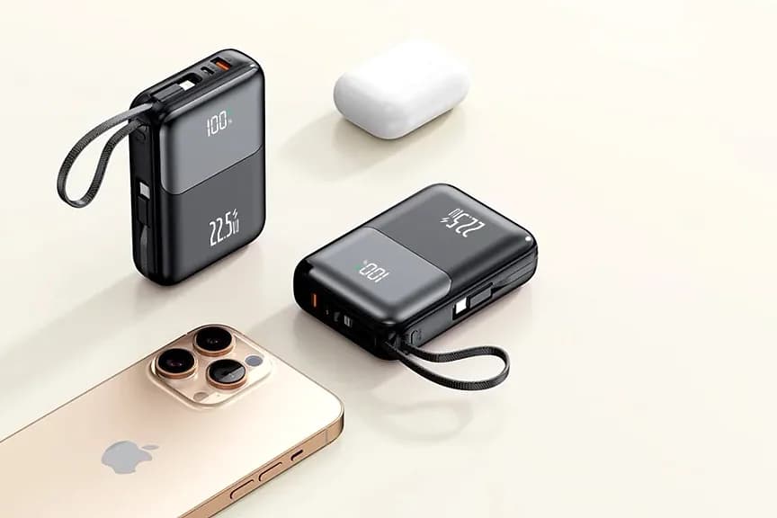 Bej zeminde iki siyah powerbank, beyaz kulaklık kutusu ve akıllı telefon.