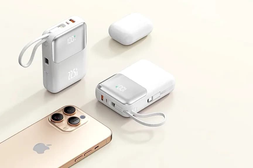 Telefon, kulaklık kutusu ve iki beyaz powerbank açık masada.
